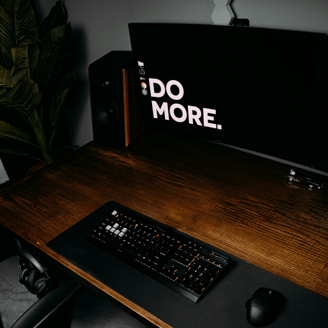 Minimalist desk setup with 'DO MORE' neon sign and laptop promoting workplace productivity.