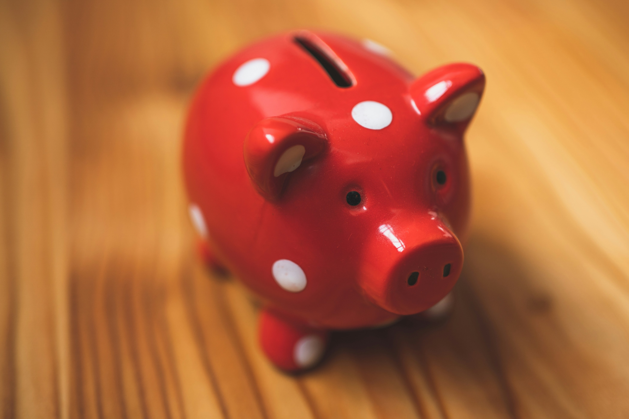 Red polka dot piggy bank on wooden surface with coins representing financial services and banking chatbot solutions