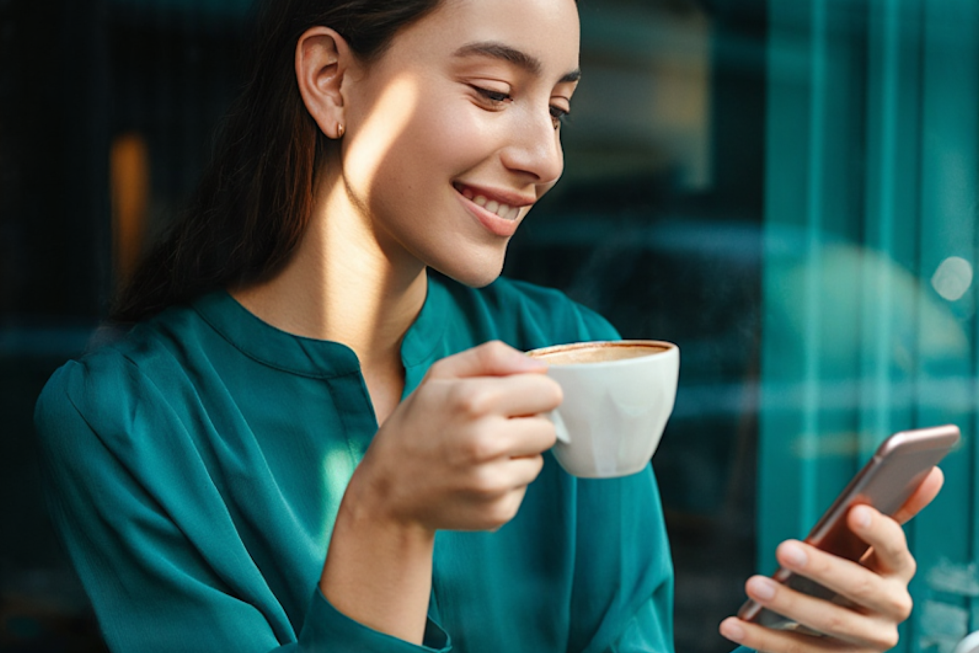 Professional woman in teal blazer holding coffee cup and smartphone capturing lead information.