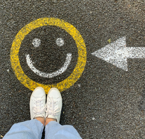 Person standing on street pavement with yellow smiley face and directional arrow showing customer journey and global accessibility