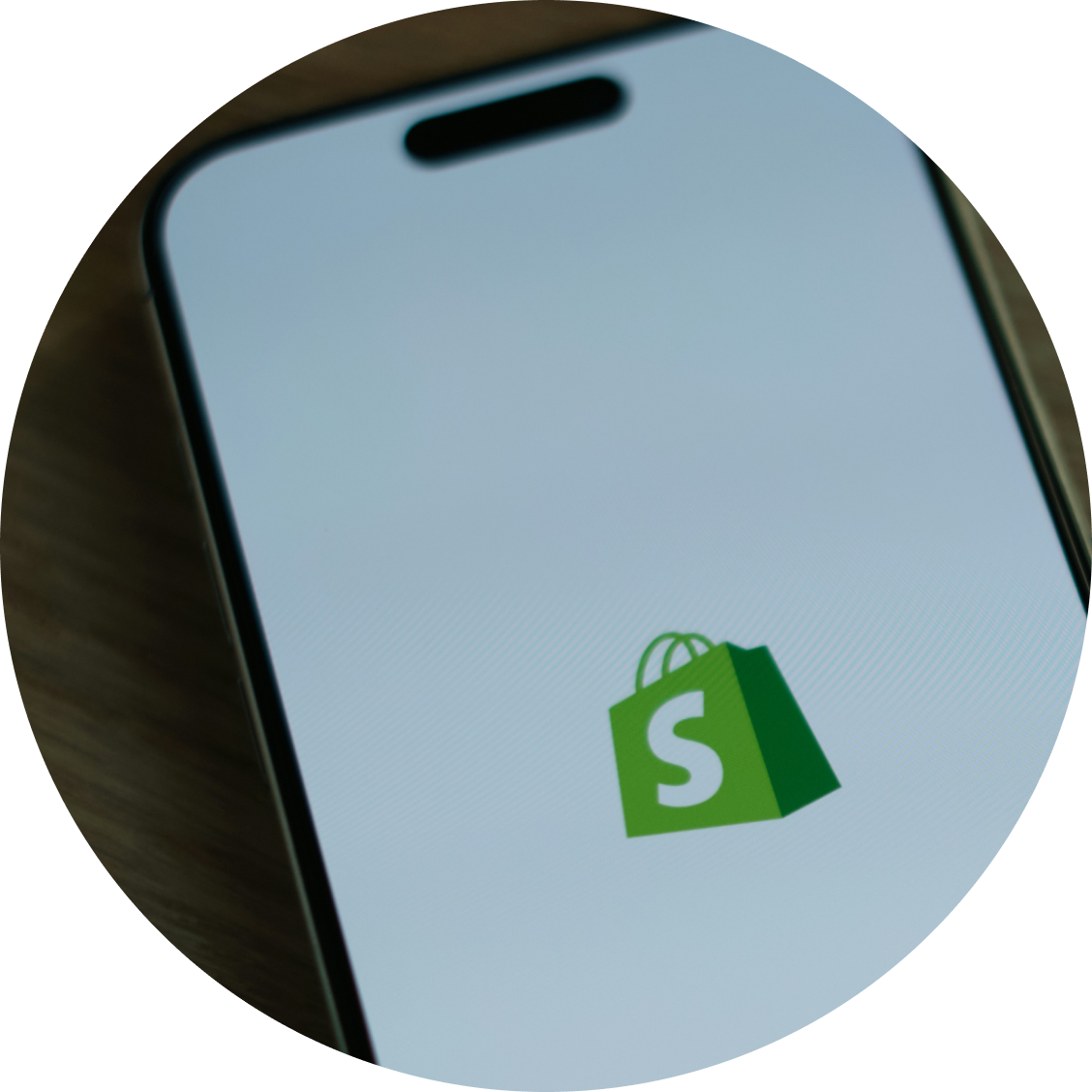 Shopify shopping bag with green logo on light blue surface representing e-commerce platform integration